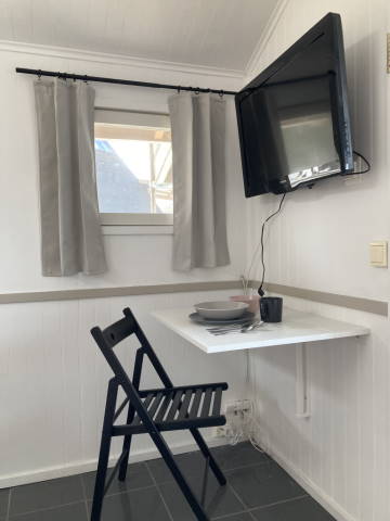 Small cabin after makeover, view of the corner with TV mounted on the wall and folding table attached to the wall