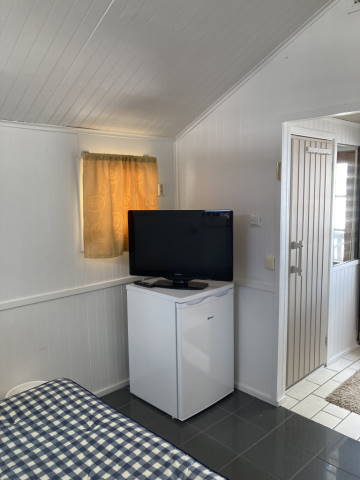 Small cabin before makeover, view of the corner with small fridge and flatscreen TV on top of it